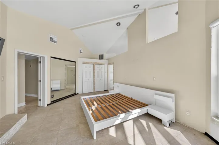 This room features vaulted ceilings, recessed lighting, and tile flooring