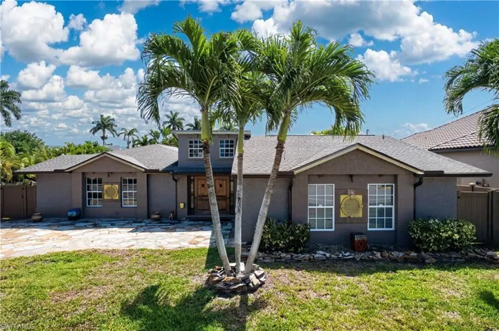 The property features a stucco exterior, multiple white-framed windows, and a prominent front entrance with double doors