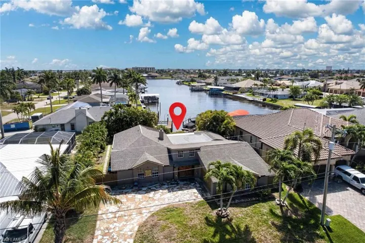This property features a spacious paved driveway, a well-maintained lawn, and mature palm trees