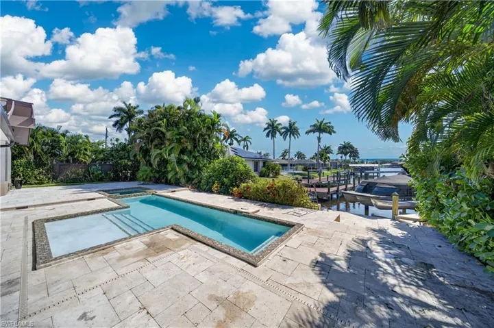 The property features a swimming pool with an integrated spa, surrounded by a paved patio