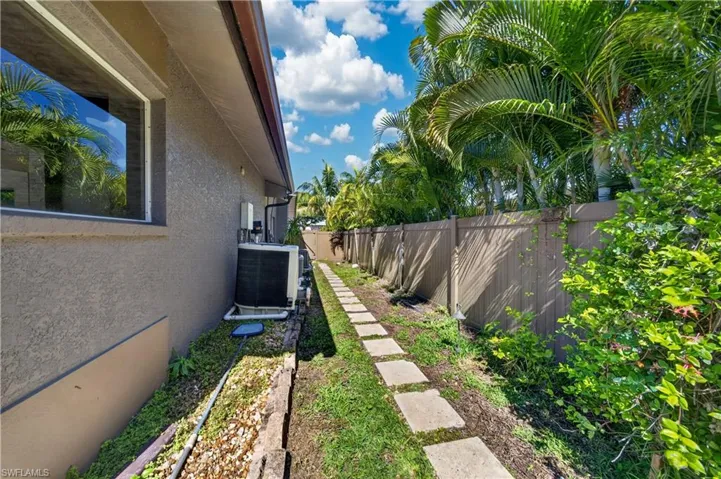 The property features a private side yard with a stepping stone pathway, established landscaping, and a privacy fence