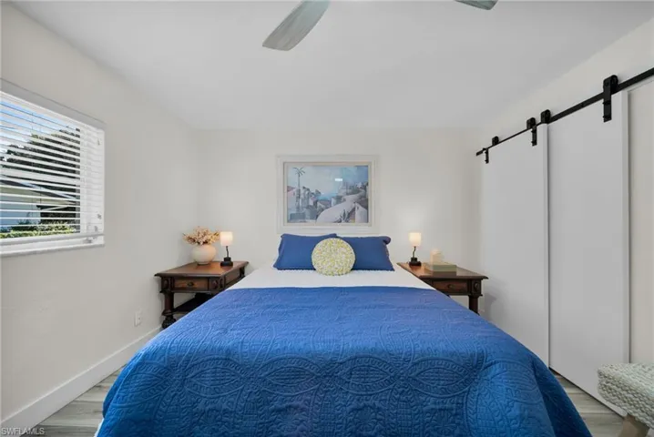 Bedroom featuring a barn door, wood finished floors, and a ceiling fan