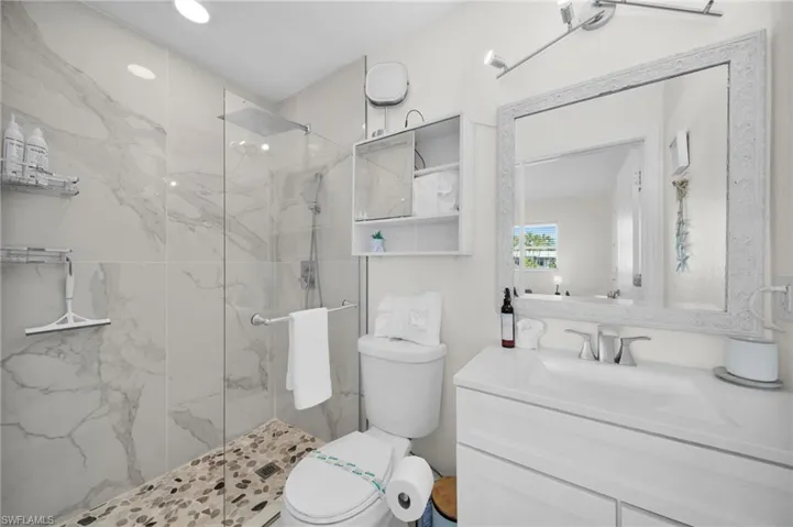 Full bathroom with vanity, a marble finish shower, and recessed lighting