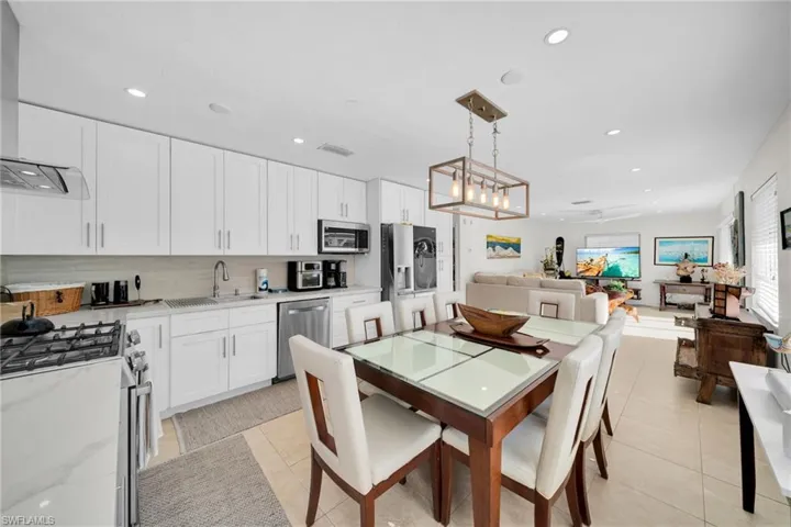 Kitchen featuring stainless steel appliances, white cabinetry, custom exhaust hood, open floor plan, and recessed lighting