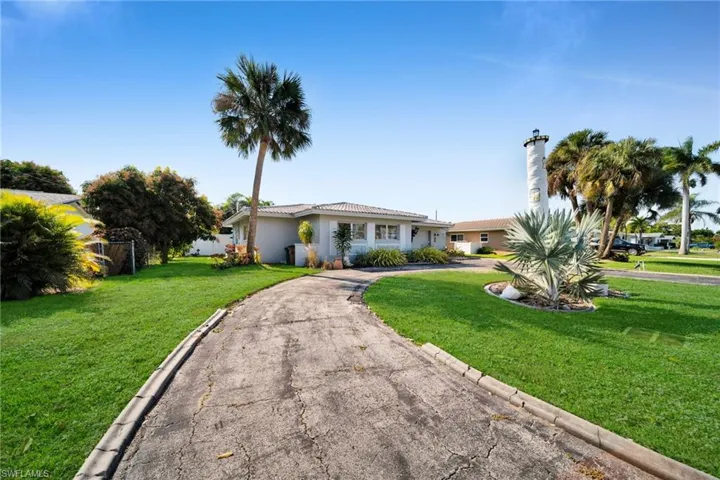 Ranch-style home featuring curved driveway, a tiled roof, and stucco siding