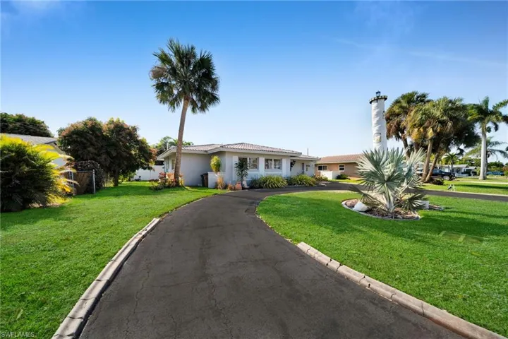 Single story home featuring a front lawn, driveway, a tiled roof, and stucco siding