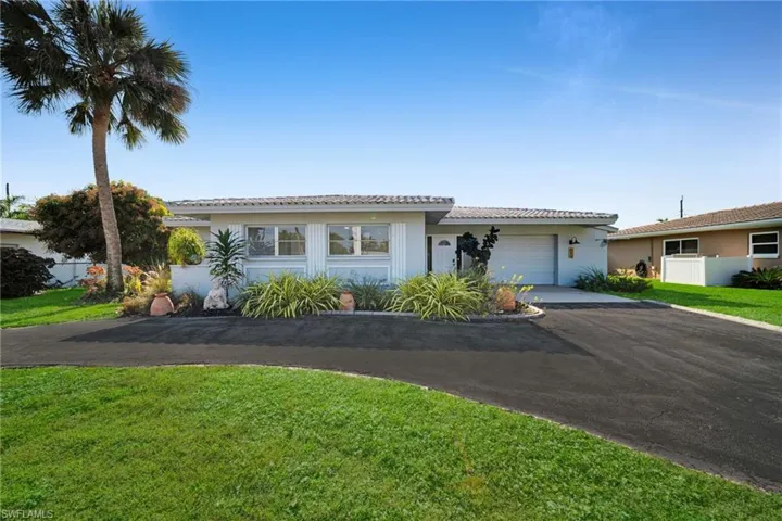 Single story home with asphalt driveway, a front yard, a tile roof, and a garage