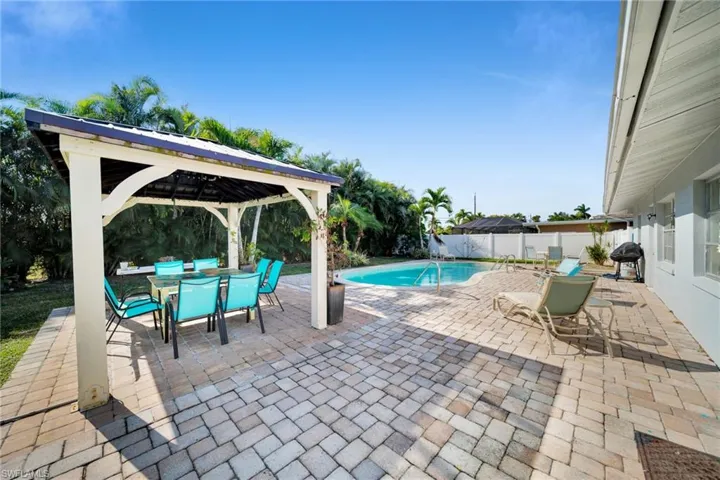 View of swimming pool with outdoor dining space, a patio area, grilling area, a gazebo, and a fenced backyard