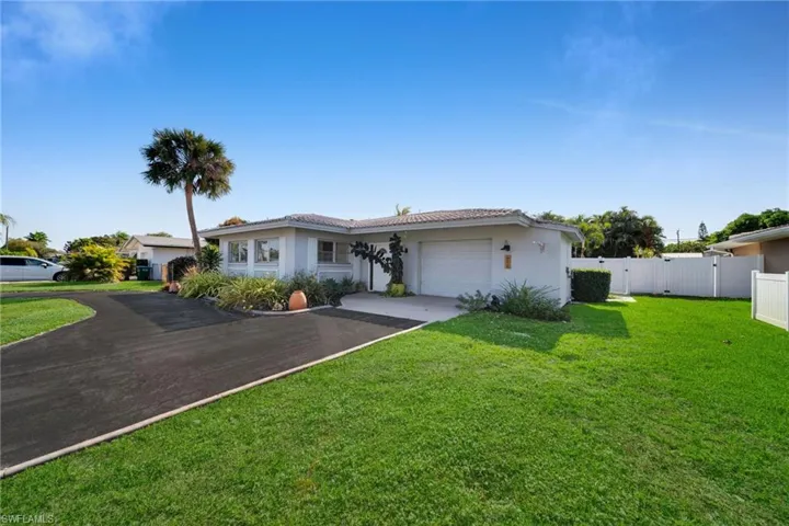 Single story home featuring a garage, driveway, stucco siding, and a gate