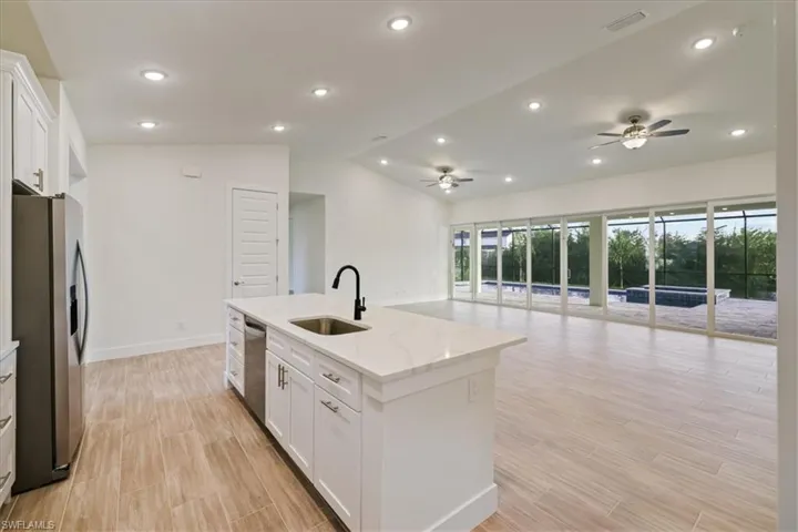 Kitchen featuring white cabinetry, lofted ceiling, open floor plan, appliances with stainless steel finishes, and recessed lighting