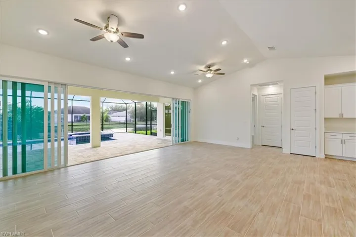 Spare room featuring wood finish floors, lofted ceiling, ceiling fan, and recessed lighting
