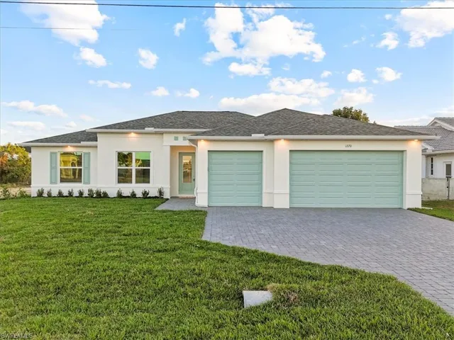 Prairie-style house featuring stucco, a front yard, and decorative driveway