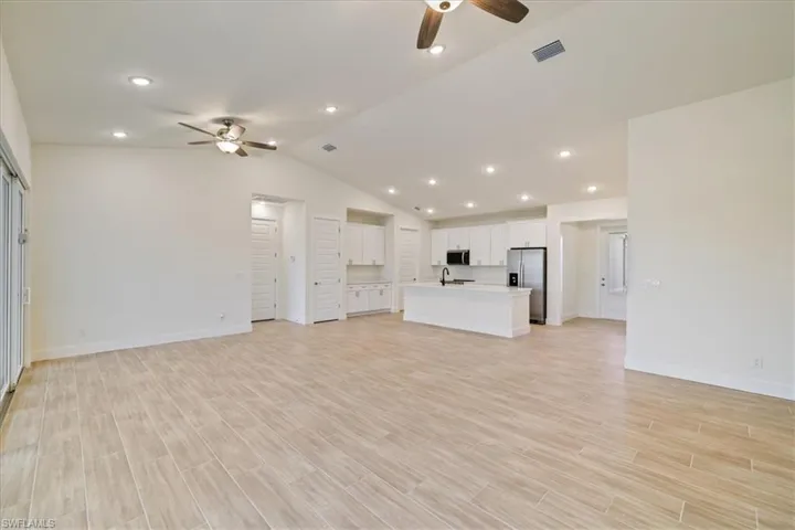 Unfurnished living room with recessed lighting, a ceiling fan, lofted ceiling, and wood tiled floors