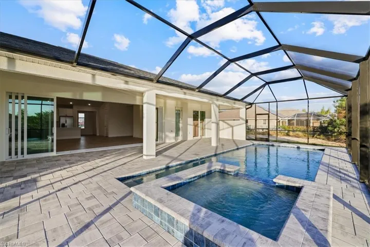 View of pool featuring a sunroom, a pool with connected hot tub, a patio, and a lanai