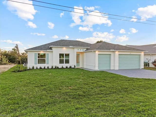 View of front of house featuring decorative driveway, a front lawn, stucco siding, and an attached garage