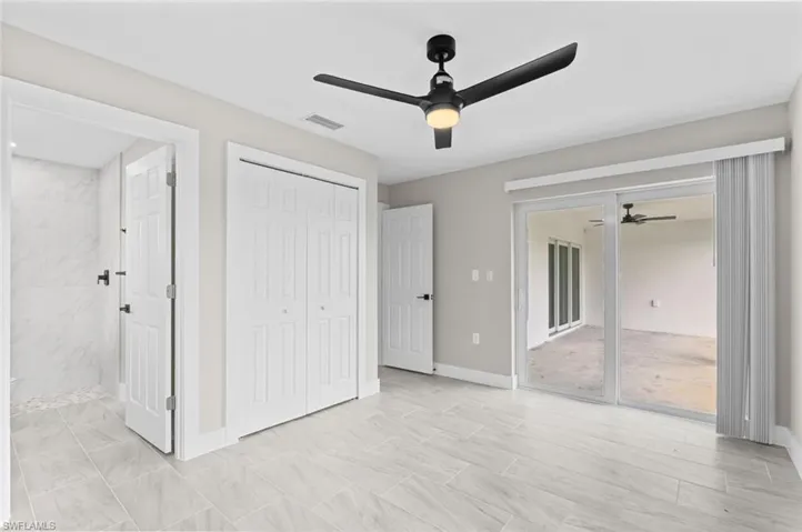 Unfurnished bedroom featuring a ceiling fan, ensuite bath, and a closet