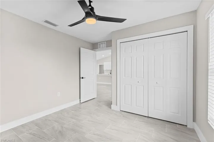 Unfurnished bedroom with a closet, a ceiling fan, and multiple windows