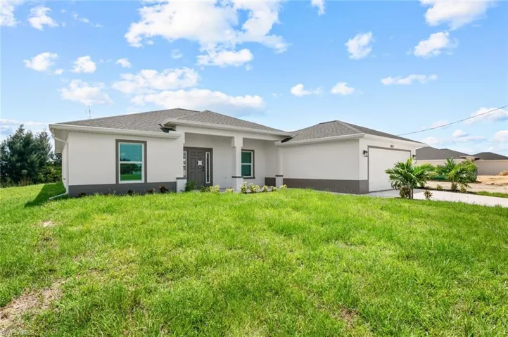 Prairie-style house with a garage, stucco siding, a front yard, and concrete driveway
