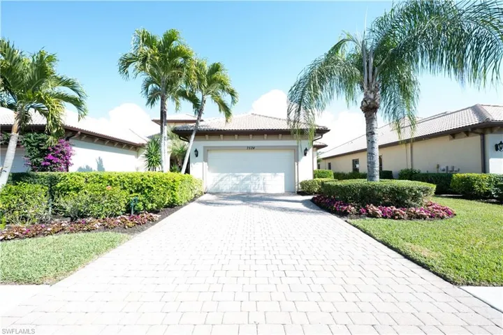 View of front facade with decorative driveway, stucco siding, a tile roof, a garage, and a front lawn
