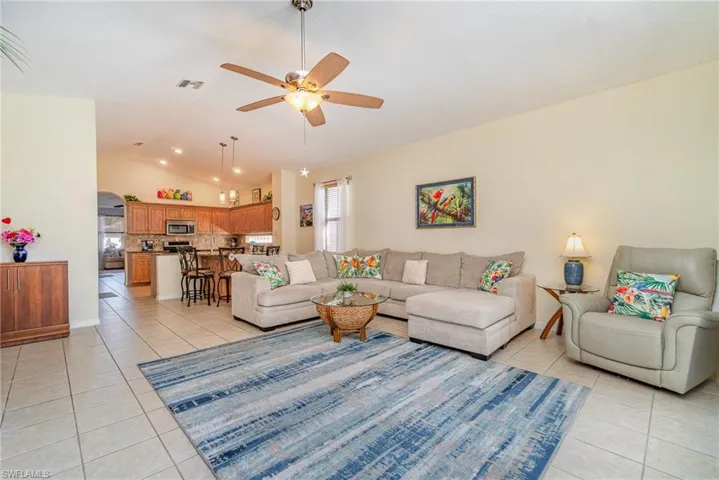 Living room featuring lofted ceiling, visible vents, a ceiling fan, and light tile patterned flooring