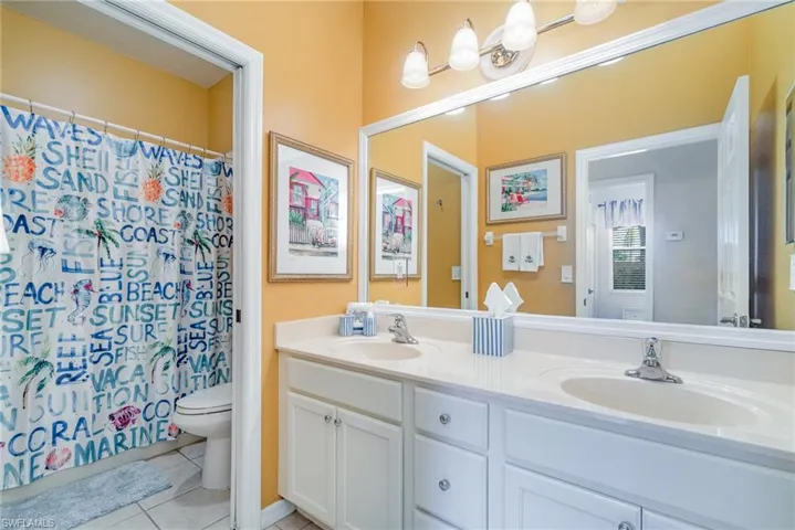 Full bath featuring toilet, double vanity, a sink, and tile patterned floors