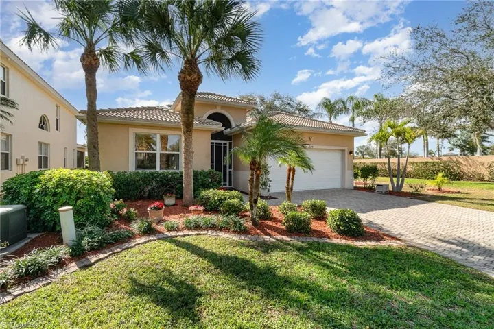 Mediterranean / spanish home featuring a tile roof, an attached garage, decorative driveway, a front yard, and stucco siding