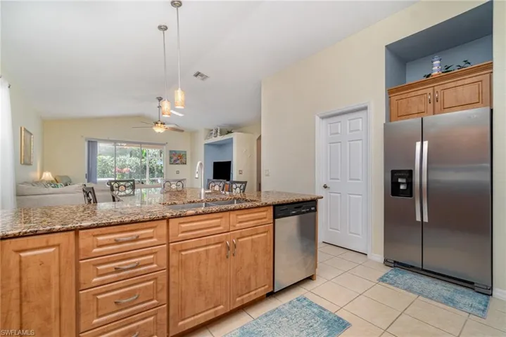 Kitchen featuring open floor plan, stainless steel appliances, light stone counters, and a sink