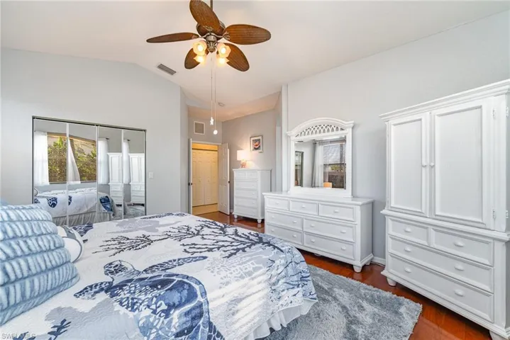 Bedroom with lofted ceiling, dark wood-style flooring, visible vents, and ceiling fan