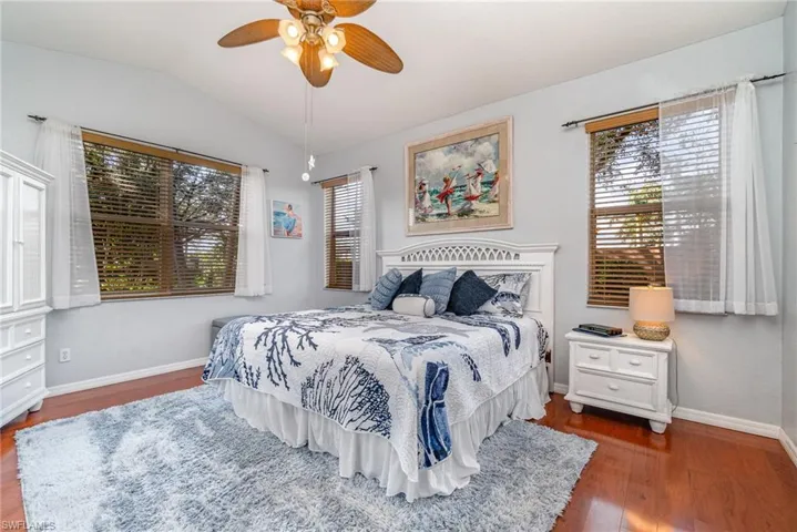 Bedroom with lofted ceiling, ceiling fan, dark wood finished floors, and baseboards