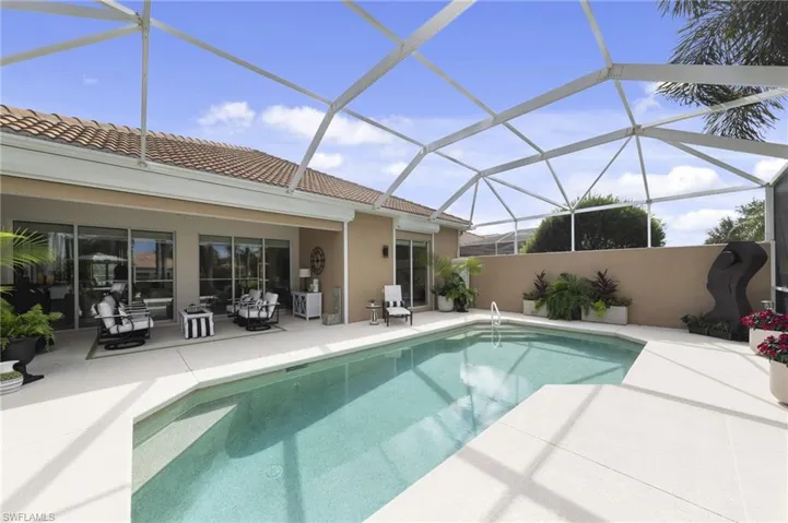 Screen-enclosed patio featuring a concrete pool deck, in-ground swimming pool, masonry privacy wall, and sliding glass doors