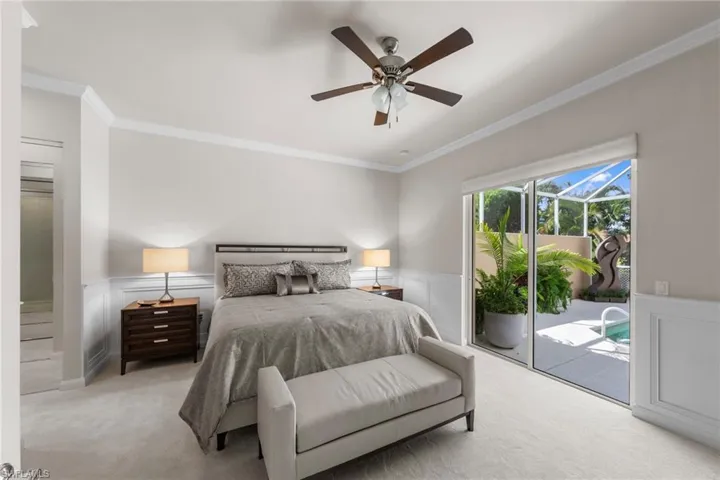 Neutral-toned walls featuring wainscoting, ceiling fan with integrated light fixture, and sliding glass doors with access to a screened-in outdoor area