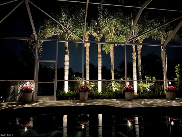 Screened lanai featuring a paved deck, aluminum enclosure, and mature palm trees
