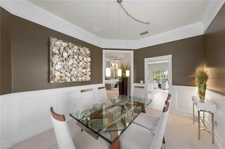 Dining room featuring crown molding, wainscoting, and a multi-pendant track lighting fixture