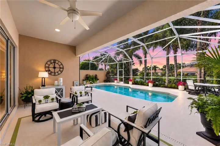 Covered outdoor living area featuring a neutral-toned concrete patio, ceiling-mounted paddle fan, screened-in enclosure, and an in-ground swimming pool