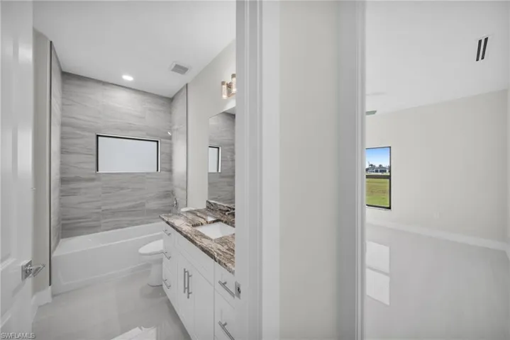 Bathroom featuring vanity, bathtub / shower combination, healthy amount of natural light, and recessed lighting