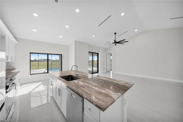 Kitchen with white cabinets, dark stone counters, a center island with sink, appliances with stainless steel finishes, and healthy amount of natural light