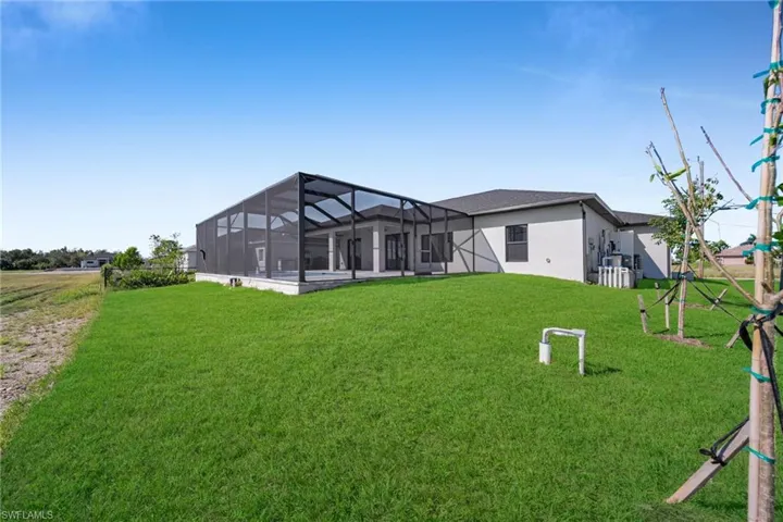 Rear view of house with a lawn, glass enclosure, and a sunroom