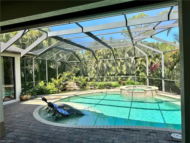 View of pool featuring a patio area, glass enclosure and in ground hot tub