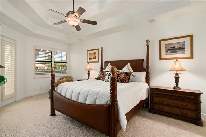 Carpeted Master bedroom featuring ceiling fan, a raised ceiling, and crown molding