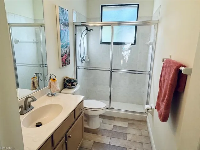 Bathroom with an enclosed shower, vanity, and toilet