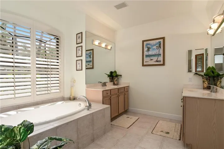 Master Bathroom featuring dual vanity, a relaxing tiled bath, and tile flooring