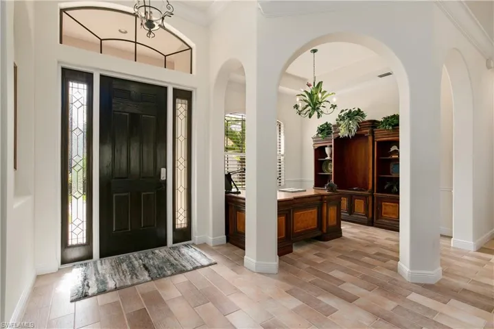 Entryway with study featuring crown molding and light wood-like tile flooring