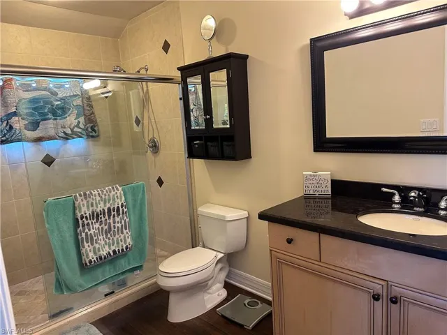 Guest house Bath  with an enclosed shower, wood-type flooring, vanity, and toilet