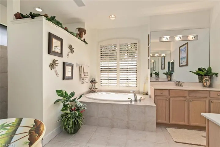 Master Bathroom with tile flooring, a relaxing tiled bath, and vanity