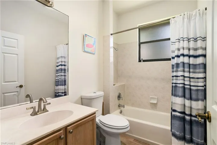 Full bathroom with tile floors, shower / tub combo with curtain, toilet, and vanity