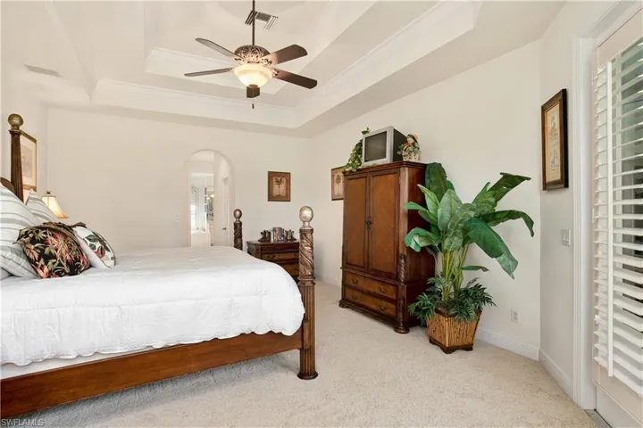 Master Bedroom with ceiling fan, a tray ceiling, and light colored carpet