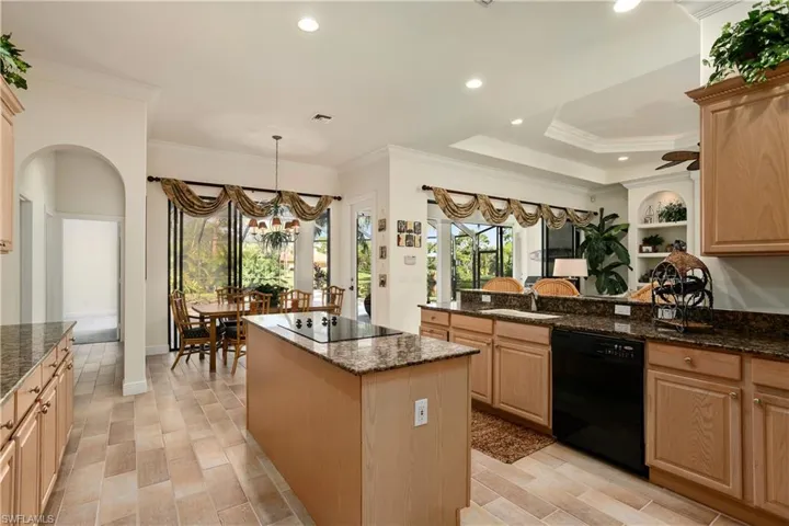 Kitchen featuring black appliances, ornamental molding, dark stone counters, and a kitchen island