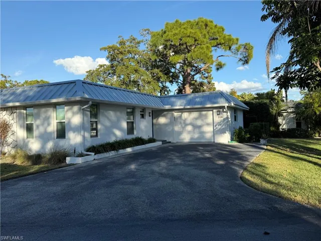 Ranch-style house featuring driveway, a metal roof, a garage, and stucco siding