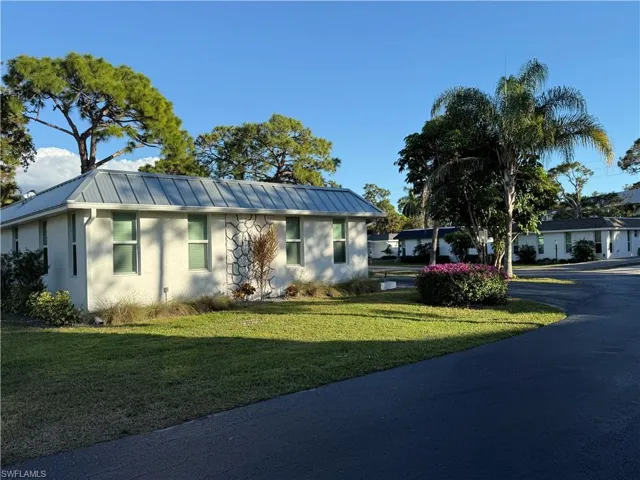 Ranch-style house featuring a metal roof, a front lawn, stucco siding, and a standing seam roof