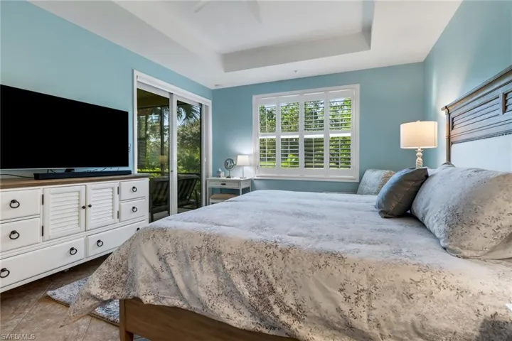 Bedroom featuring a raised ceiling, ceiling fan, and access to outside